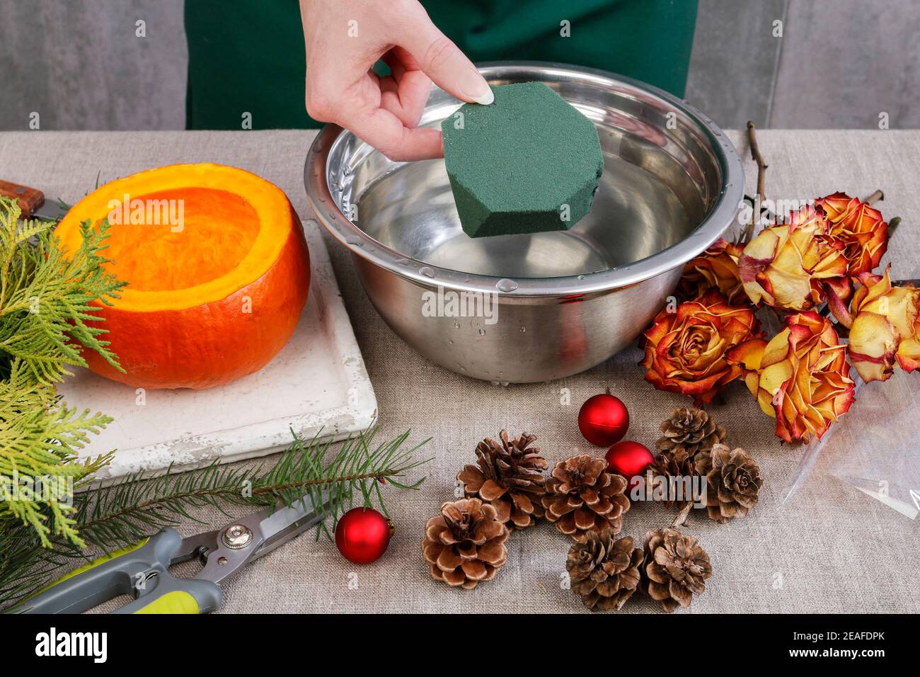 Come fare decorazione di Natale durevole fatta di rose secche, ramoscelli di abete e baubles. Disposizione floreale all'interno della zucca. Passo dopo passo, TUto Foto Stock