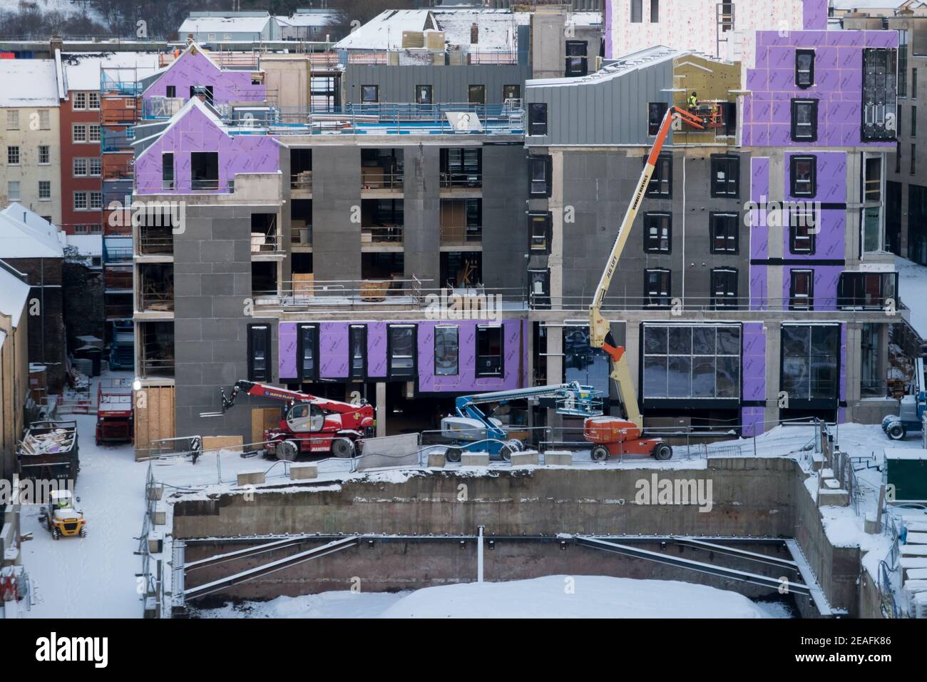 Operai su un picker di ciliegio che installa pannelli di rivestimento in un nuovo blocco di appartamenti di lusso nel centro della città di Edimburgo. Foto Stock