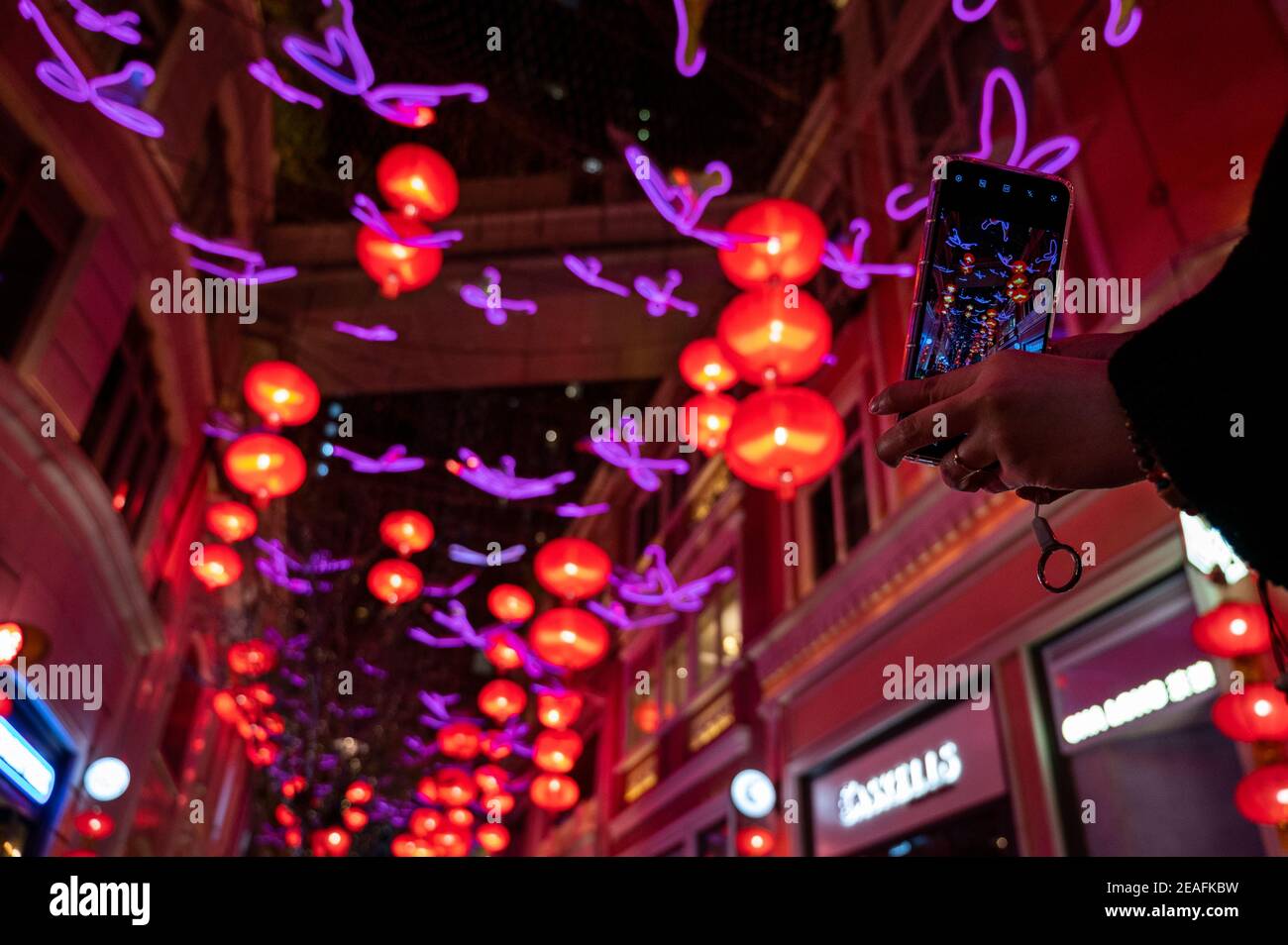 Hong Kong, Cina. 09 febbraio 2021. Una donna usa il suo smartphone per scattare foto di centinaia di lanterne rosse appese al soffitto di Lee Tung Avenue a Hong Kong per celebrare il festival cinese del capodanno lunare e l'anno dell'Ox. Credit: SOPA Images Limited/Alamy Live News Foto Stock