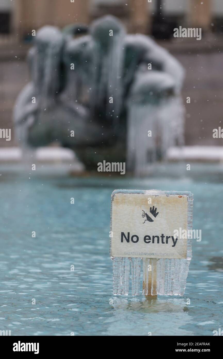 Londra, Regno Unito. 9 febbraio 2021. Regno Unito Meteo: Un segno congelato di fronte a una fontana ghiacciata coperta di ghiaccio in Trafalgar Square durante le lievi nevicate mentre il freddo portato da Storm Darcy continua. Credit: Stephen Chung / Alamy Live News Foto Stock