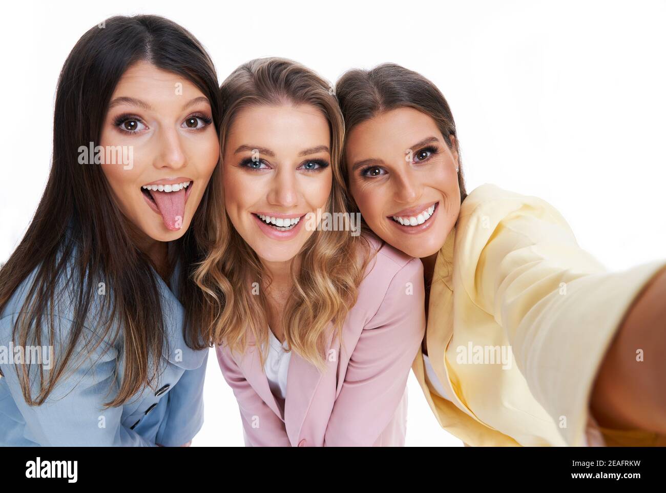 Tre donne in tute pastello che posano su sfondo bianco Foto Stock