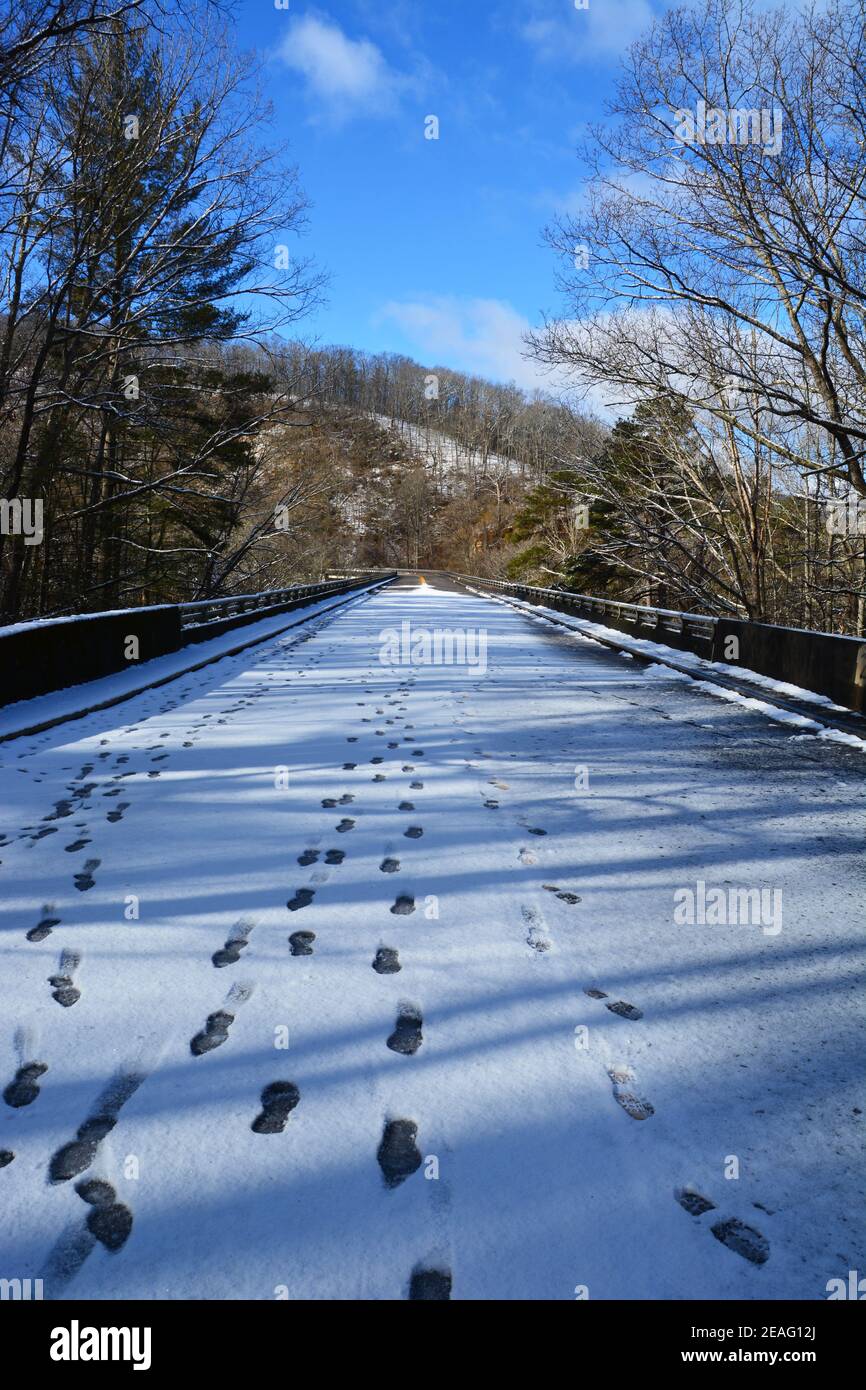 Impronte nel ghiaccio e neve che ricopra la strada su una sezione della Blue Ridge Parkway chiusa alle auto per l'inverno vicino Asheville, Carolina del Nord Foto Stock