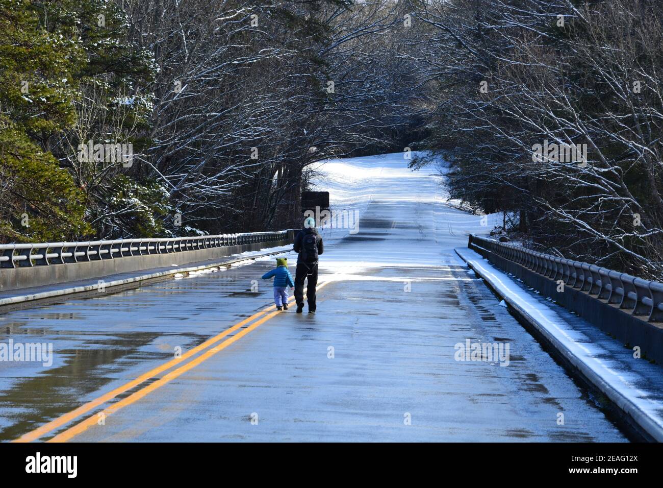 Una madre cammina con il suo bambino lungo una sezione della Blue Ridge Parkway che è chiusa alle automobili per l'inverno vicino Asheville, Carolina del Nord Foto Stock