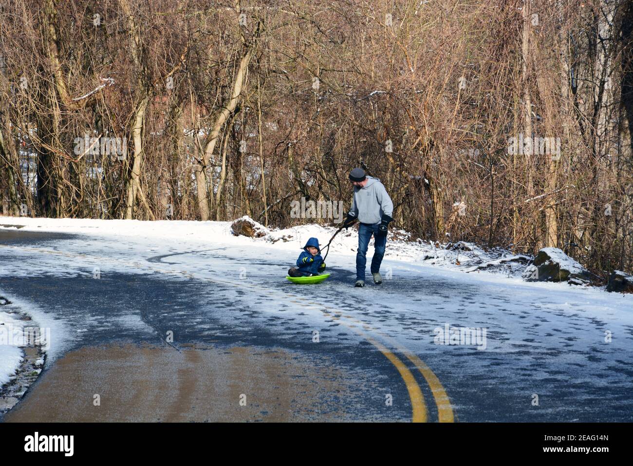 Un padre tira suo figlio in una slitta su una sezione della Blue Ridge Parkway che è chiusa alle automobili per l'inverno vicino Asheville, Carolina del Nord Foto Stock