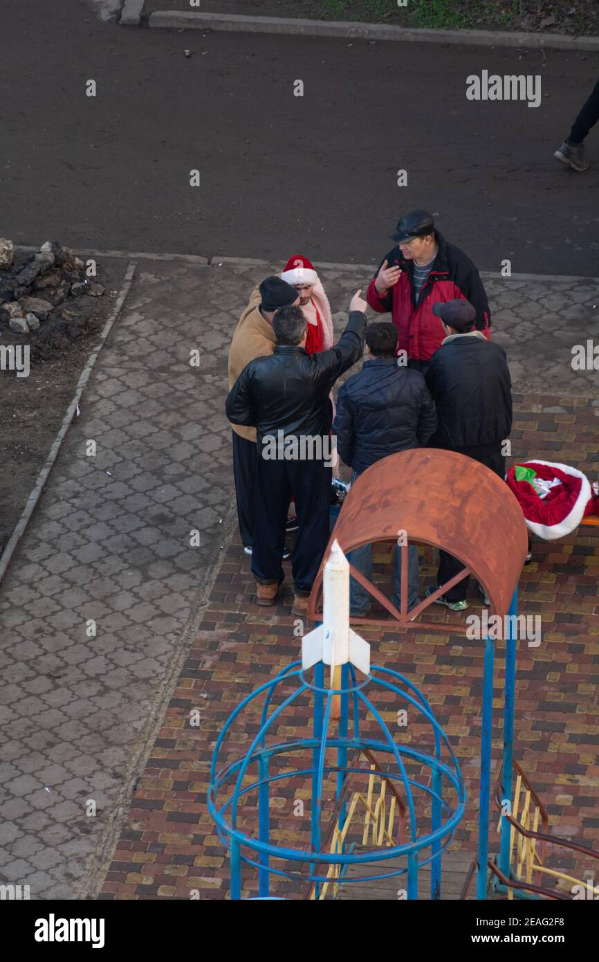 Tiraspol, Moldavia - 1 gennaio 2021: Un uomo vestito da Babbo Natale e un gruppo di uomini che bevono alcolici sul parco giochi il primo giorno di Capodanno 2 Foto Stock