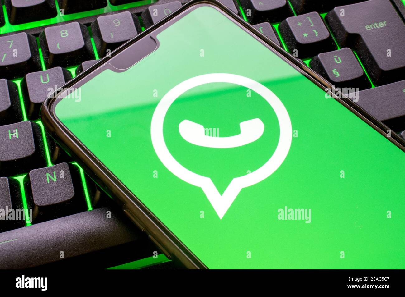 Telefono cellulare con logo Whatsapp verde sul display e tastiera colorata illuminata primo piano. Concetto di smartphone che utilizza l'applicazione di messaggistica con t Foto Stock