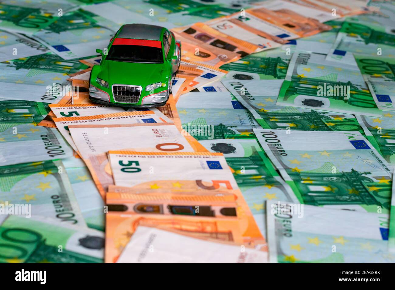 Macchinetta giocattolo su un percorso composto da cinquanta banconote da euro delimitate da banconote verdi da cento euro. Foto Stock