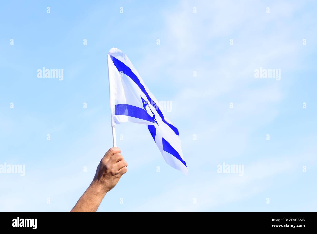 Bandiera israeliana, mano dell'uomo, cielo blu. Memoriale giorno-Yom Hazikaron, giorno di indipendenza Israele-Yom ha atzmaut concetto. Foto Stock