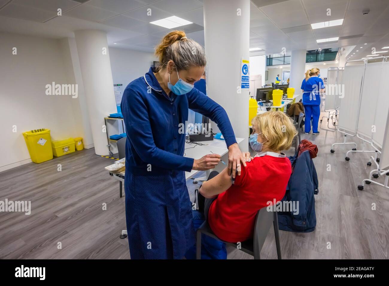 Una donna locale riceve l'iniezione di vaccinazione COVID-19 Pfizer da un'infermiera nel sito di vaccinazione Covid-19 a Woking, Surrey, nel sud-est dell'Inghilterra Foto Stock