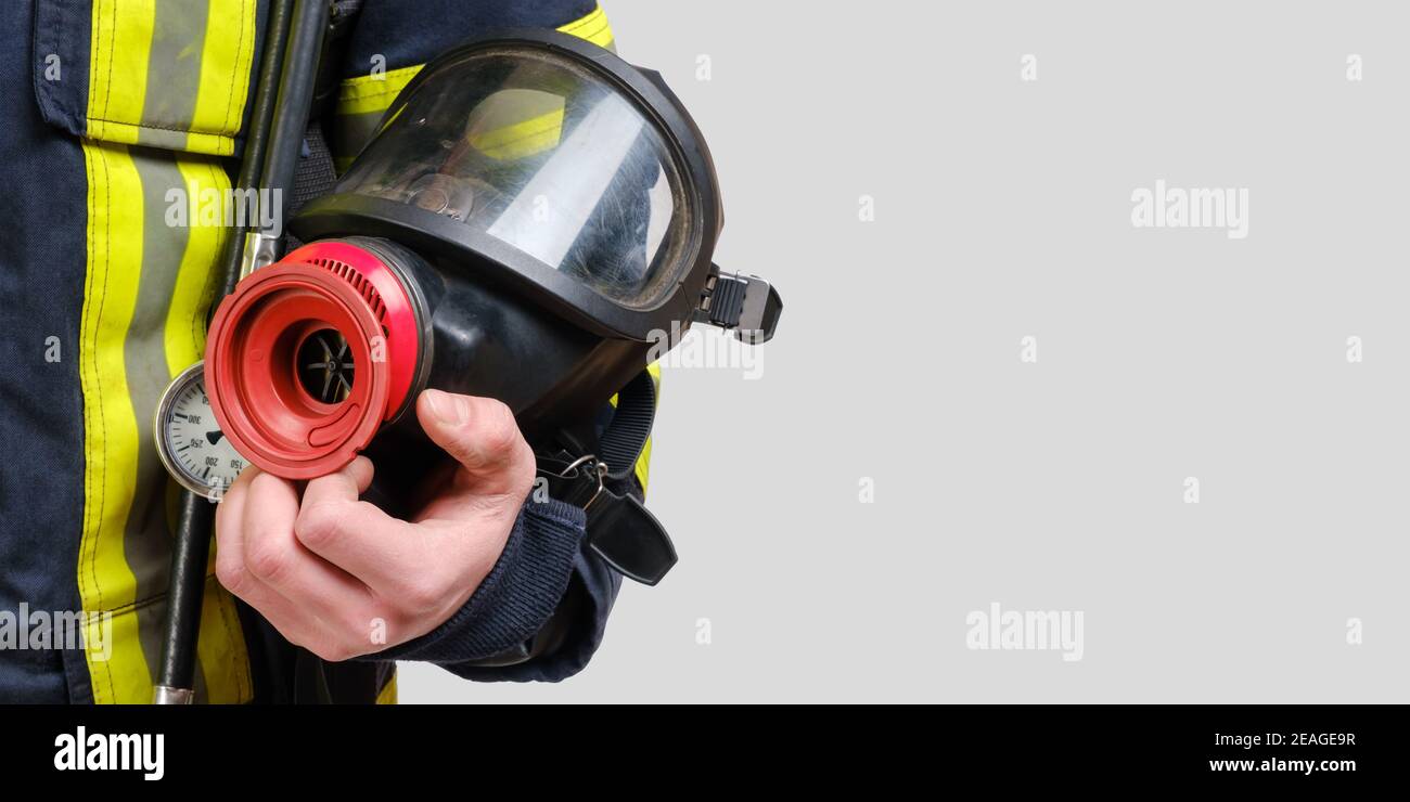 Maschera respiratoria completamente protettiva in mano a un pompiere non riconosciuto Foto Stock