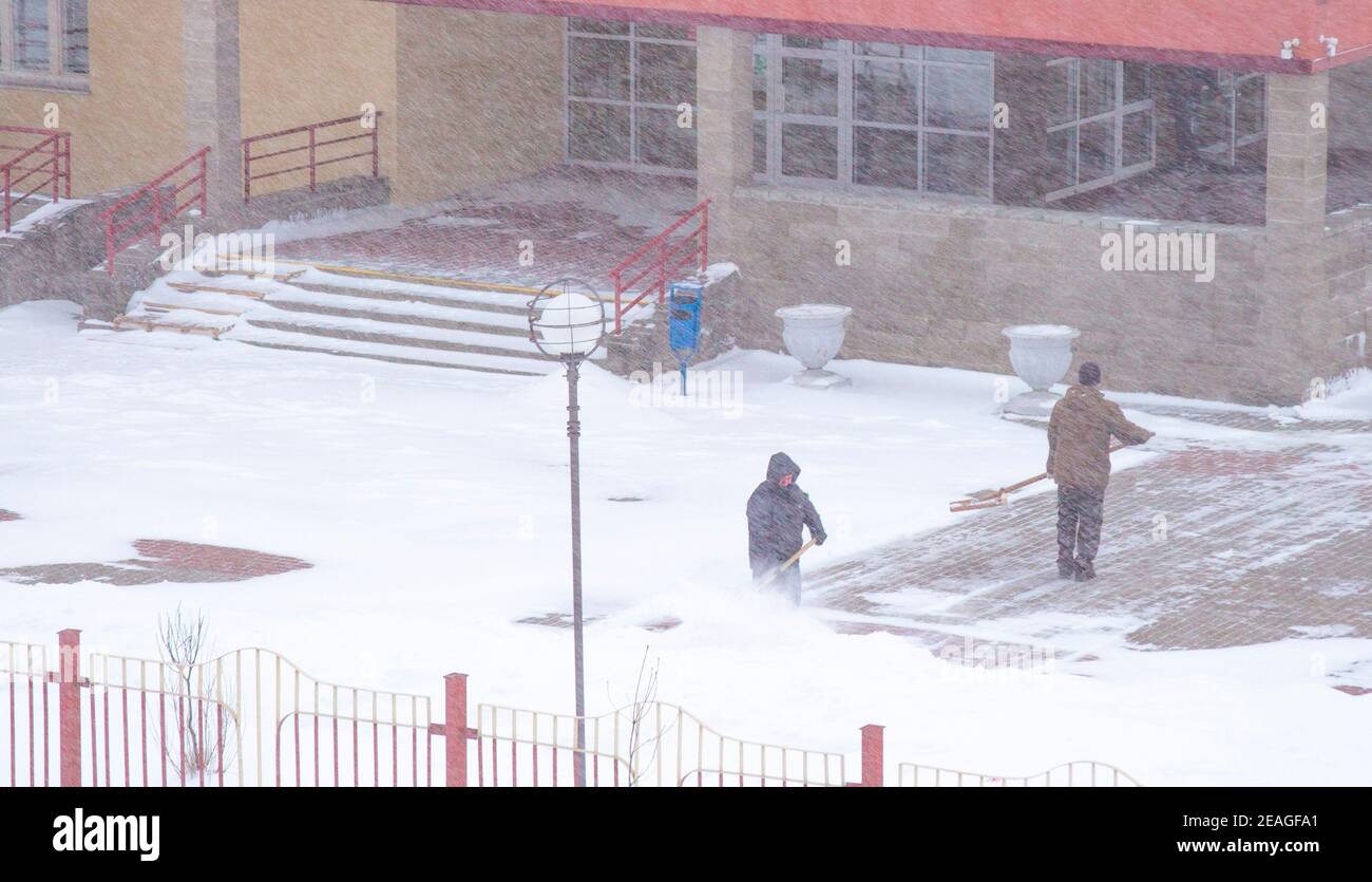 Gli operatori rimuovono la neve in inverno, lavorano con pale Foto Stock