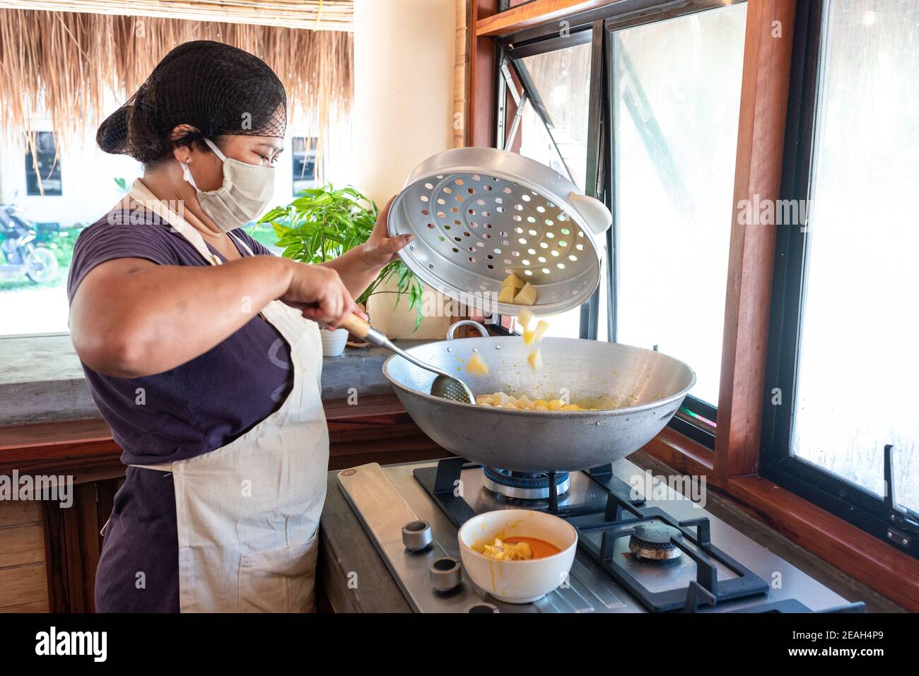 Maschera facciale due cuoci asiatiche femminili sulle verdure taglienti di servizio Cucina filippina brillante indossare maschera viso e capelli rete Chiudi su Foto Stock