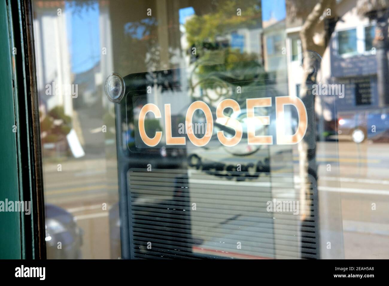 Cartello chiuso visto attraverso una porta di vetro con riflesso della strada catturato per un effetto stilizzato. Foto Stock