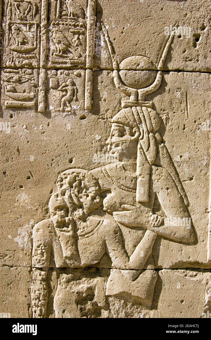 Scultura in pietra geroglifica dell'antica dea egiziana Hathor - raffigurata con una corona di corna di vacca - che succhia il faraone. Tempio di Horus, Edfu, Egy Foto Stock