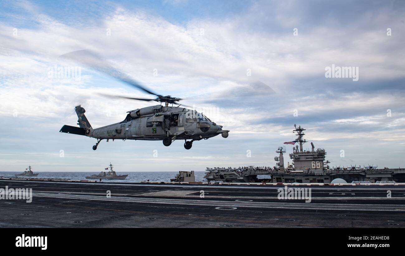 Handout foto di un falco marino MH-60S, assegnato agli "Eighballers" di Helicopter Sea Combat Squadron (HSC) 8, atterra sul ponte di volo della portaerei USS Theodore Roosevelt (CVN 71) Mentre la nave transita in formazione con il gruppo Nimitz Carrier Strike nel Mar Cinese Meridionale 9 febbraio 2021. Due gruppi di sciopero di portaerei della Marina americana hanno iniziato le operazioni nelle acque contese del Mar Cinese Meridionale martedì, l'ultimo show di capacità navali da parte dell'amministrazione Biden, in quanto si impegna a resistere fermamente contro le rivendicazioni territoriali cinesi. I vettori USS Theodore Roosevelt e USS Ni Foto Stock