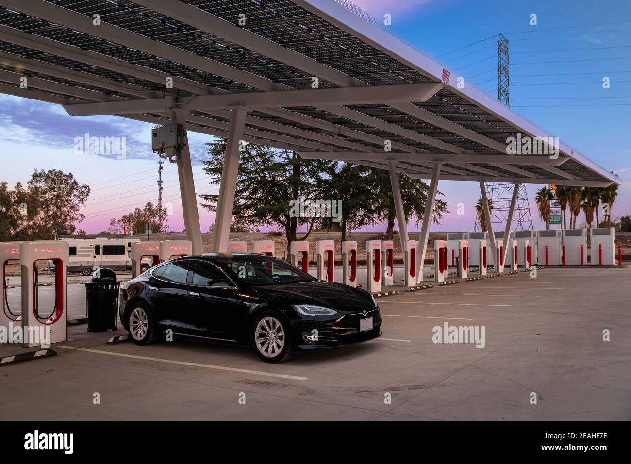 Firebaugh, USA - 21 gennaio 2021: Auto elettrica nera di lusso Tesla Model S 75D ad un Supercharger da 250 kW sulla California Highway 5 al tramonto Foto Stock