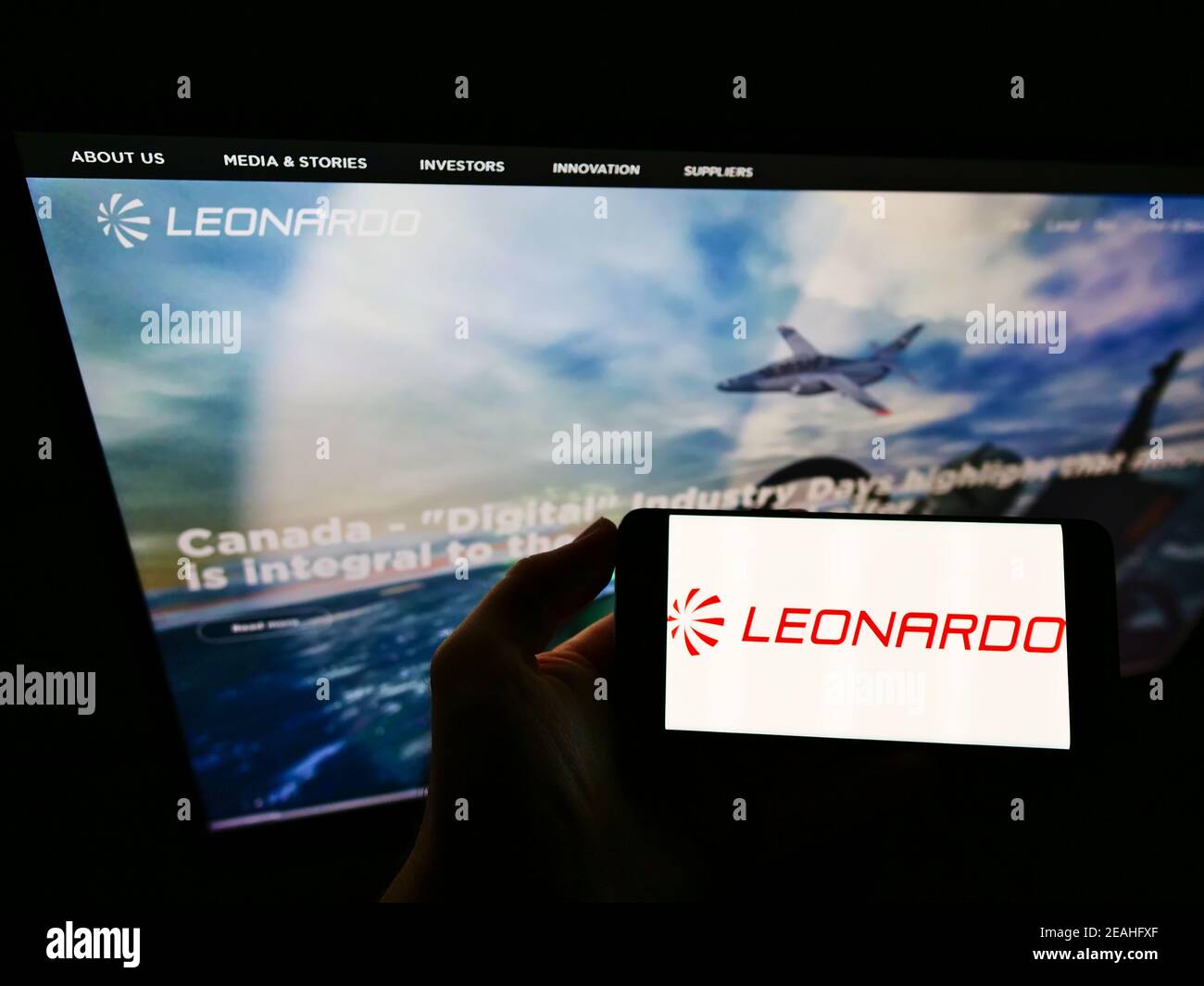 Persona titolare di un telefono cellulare con logo della società italiana di aerospazio e difesa Leonardo Spa sullo schermo davanti alla pagina web. Mettere a fuoco il display del telefono. Foto Stock