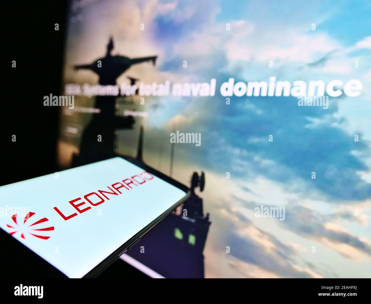 Telefono cellulare con logo della società italiana aerospaziale e difesa Leonardo S.p.A. sullo schermo davanti al sito. Mettere a fuoco al centro-sinistra del display del telefono. Foto Stock