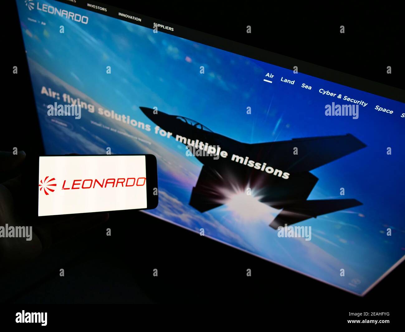 Vista ad alto angolo della persona che tiene uno smartphone con logo della società italiana di difesa Leonardo S.p.A. su schermo con sito web. Focus sul display del cellulare. Foto Stock