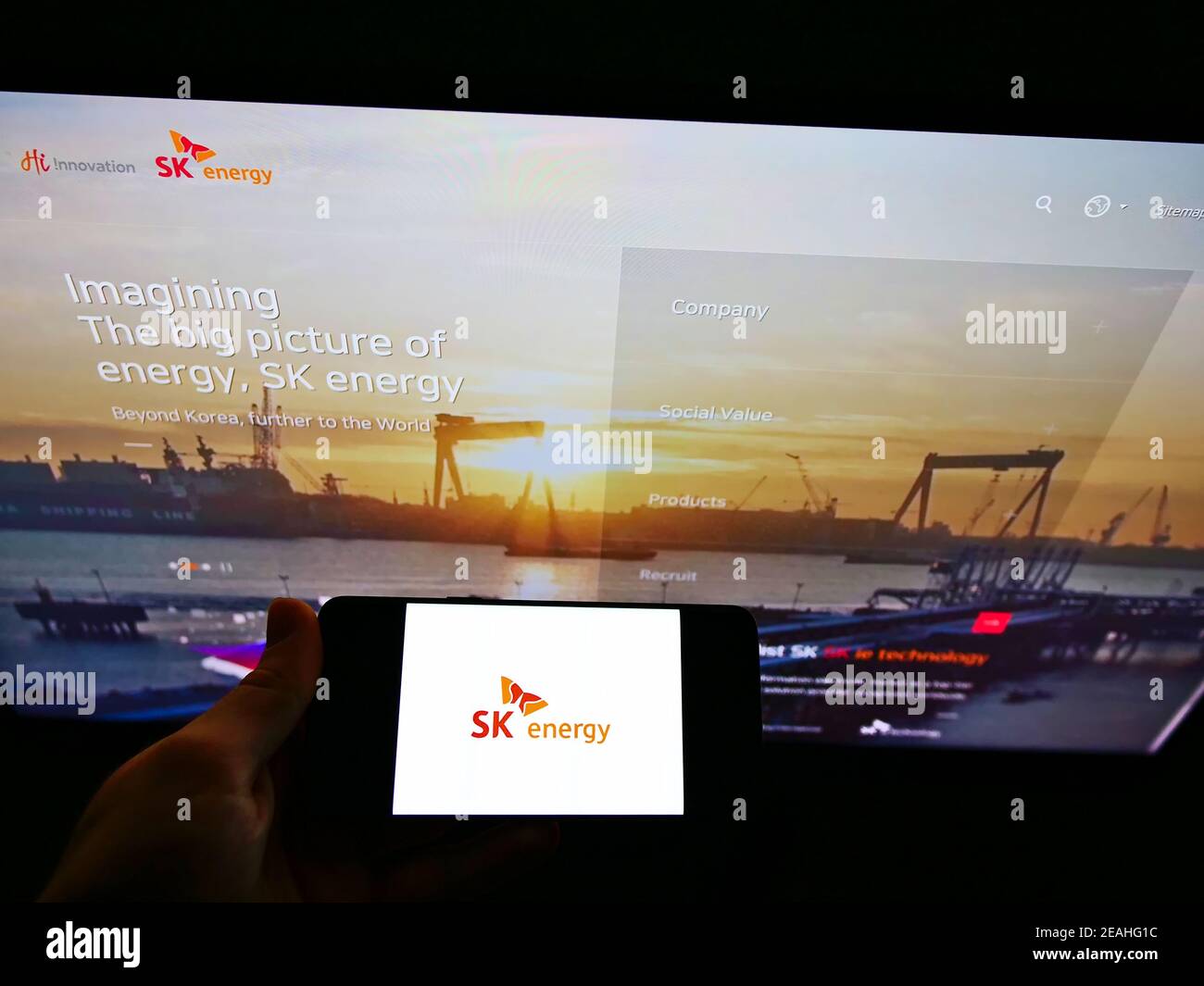 Persona che detiene smartphone con il logo aziendale della società petrolifera sudcoreana SK Energy sullo schermo di fronte al sito Web. Mettere a fuoco il display del telefono. Foto Stock
