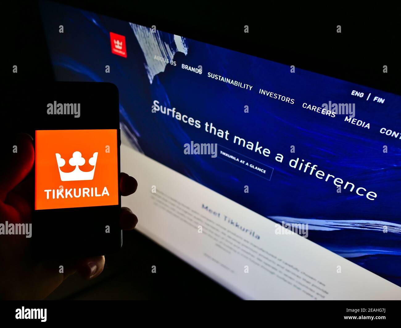 Persona che tiene lo smartphone con il logo del produttore finlandese di vernice Tikkurila Oyj sullo schermo di fronte al sito web. Mettere a fuoco il display del telefono. Foto Stock