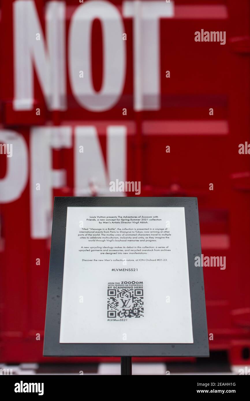 Vista verticale. Presentazione con cartello di Louis Vuitton rosso che colpisce i contenitori di spedizione sul retro. Singapore. Foto Stock