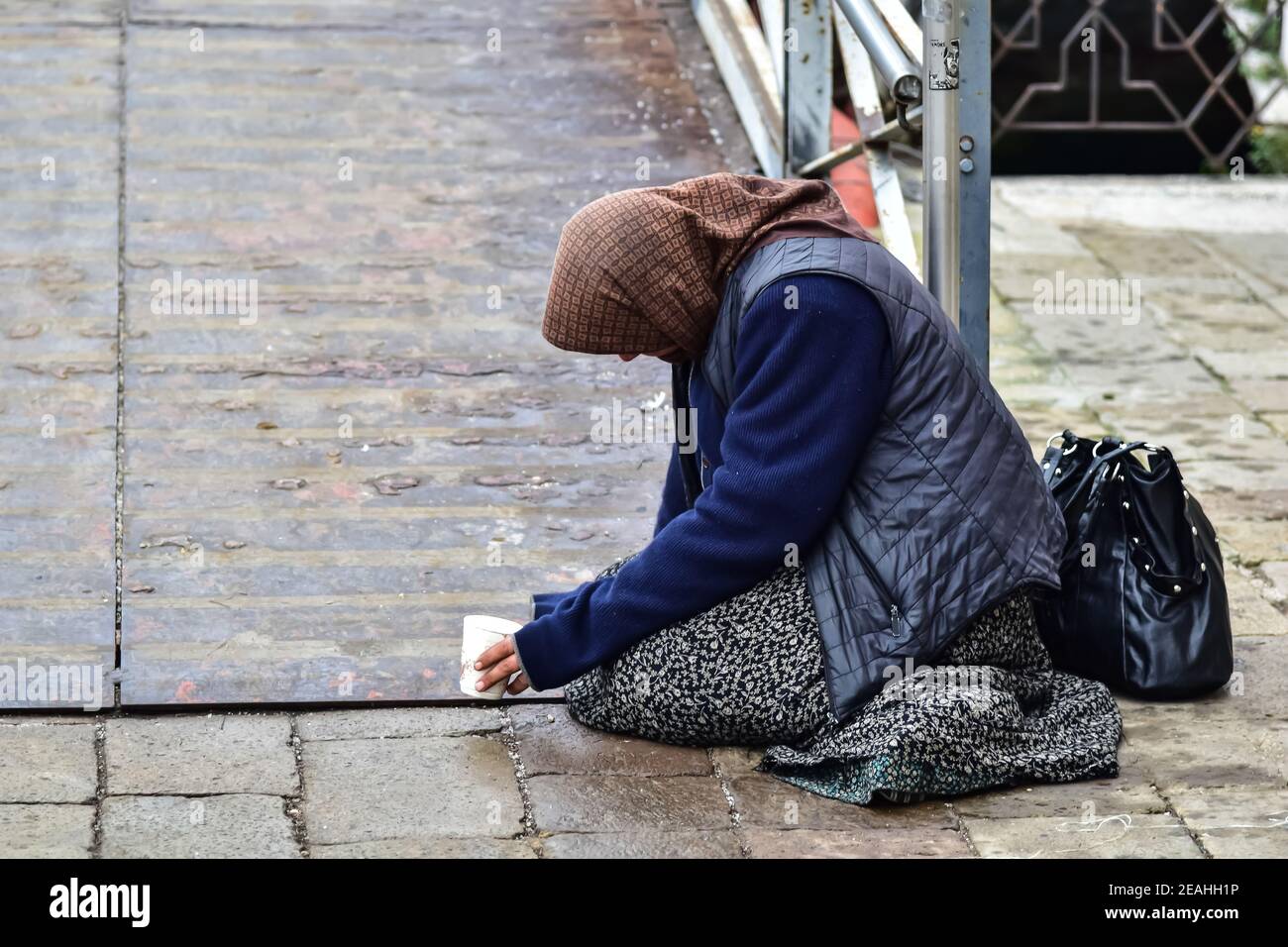 Donna gitana mendicante che mendica per soldi passersby inginocchiandosi sul massa Foto Stock