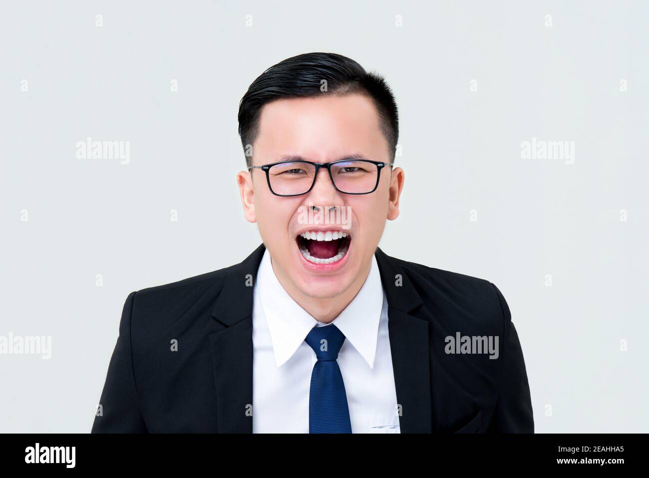 Arrabbiato uomo d'affari asiatico urlando isolato su sfondo grigio Foto Stock