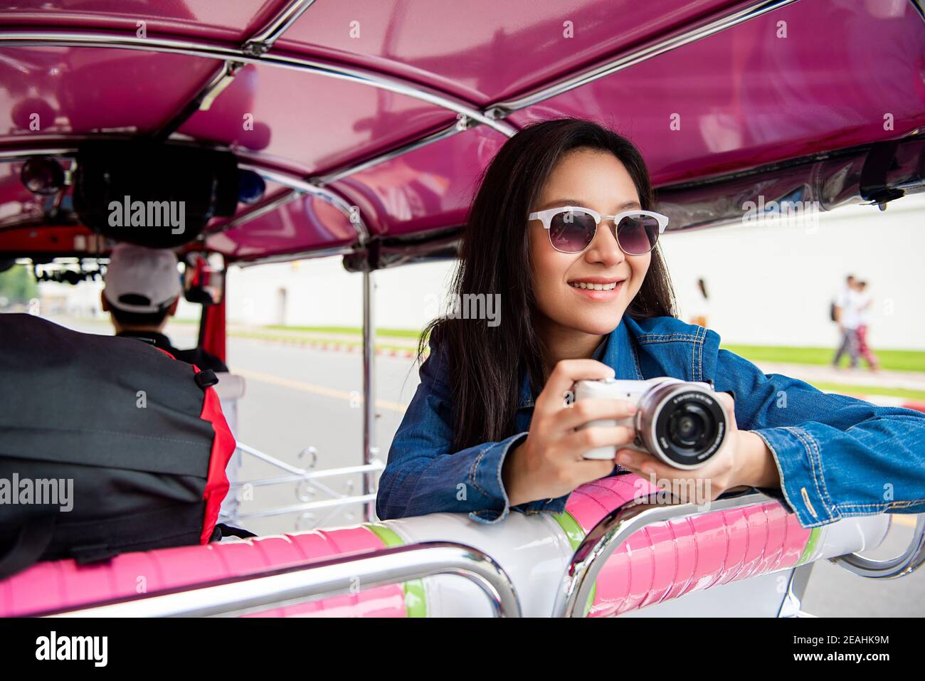 Felice sorridente donna turistica asiatica tenendo macchina fotografica su tuk tuk Taxi a Bangkok Thailandia durante le vacanze estive viaggio da solo Foto Stock