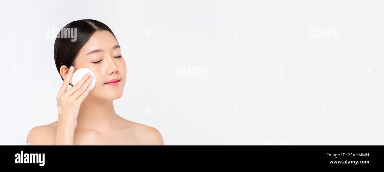 Bella donna asiatica che pulisce delicatamente il viso con il tappetino per il trucco isolato su sfondo banner bianco con spazio per la copia Foto Stock