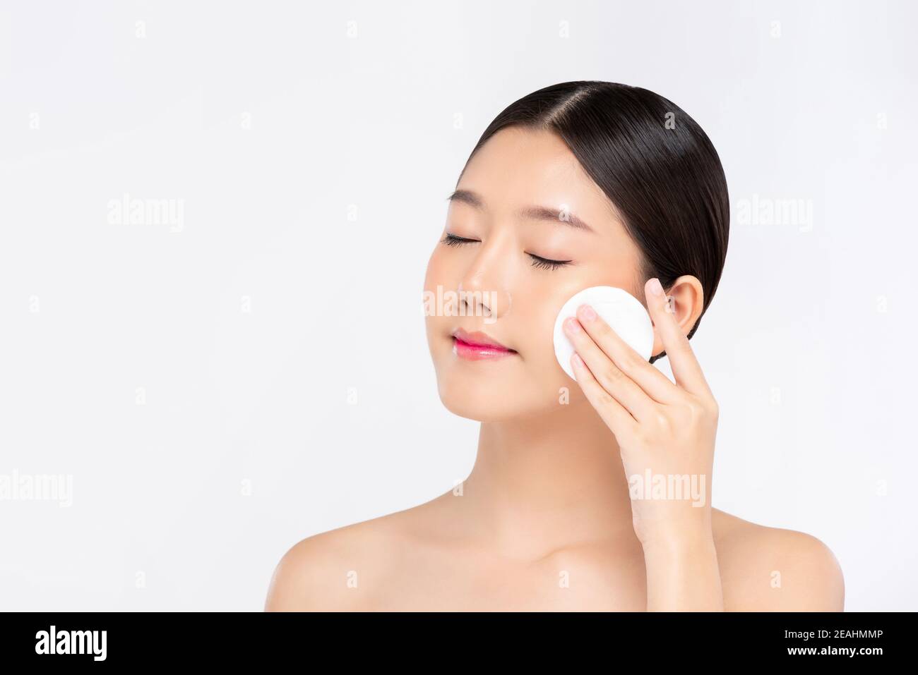 Bella donna asiatica che pulisce delicatamente il viso con il tappetino per il trucco isolato su sfondo bianco Foto Stock