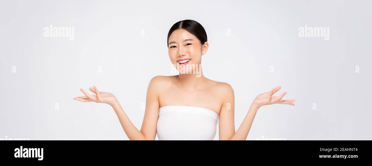 Beauty shot di giovane ragazza asiatica con pelle faccia incandescente apertura di mani vuote sullo sfondo bianco del banner Foto Stock