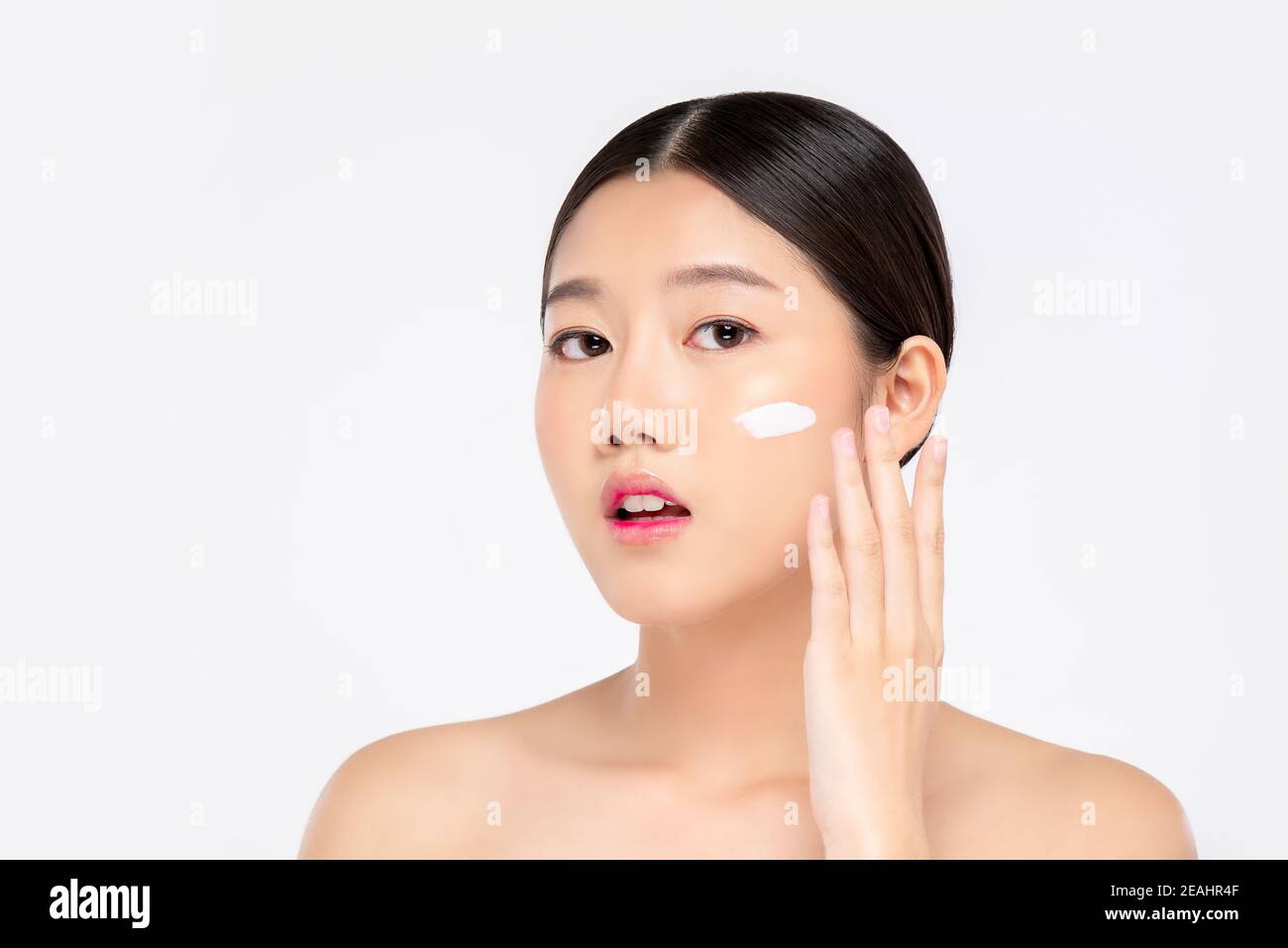 Giovane bella donna asiatica con fresco aspetto pulito applicazione crema al viso isolato su sfondo bianco per la bellezza e la cura della pelle concetti Foto Stock