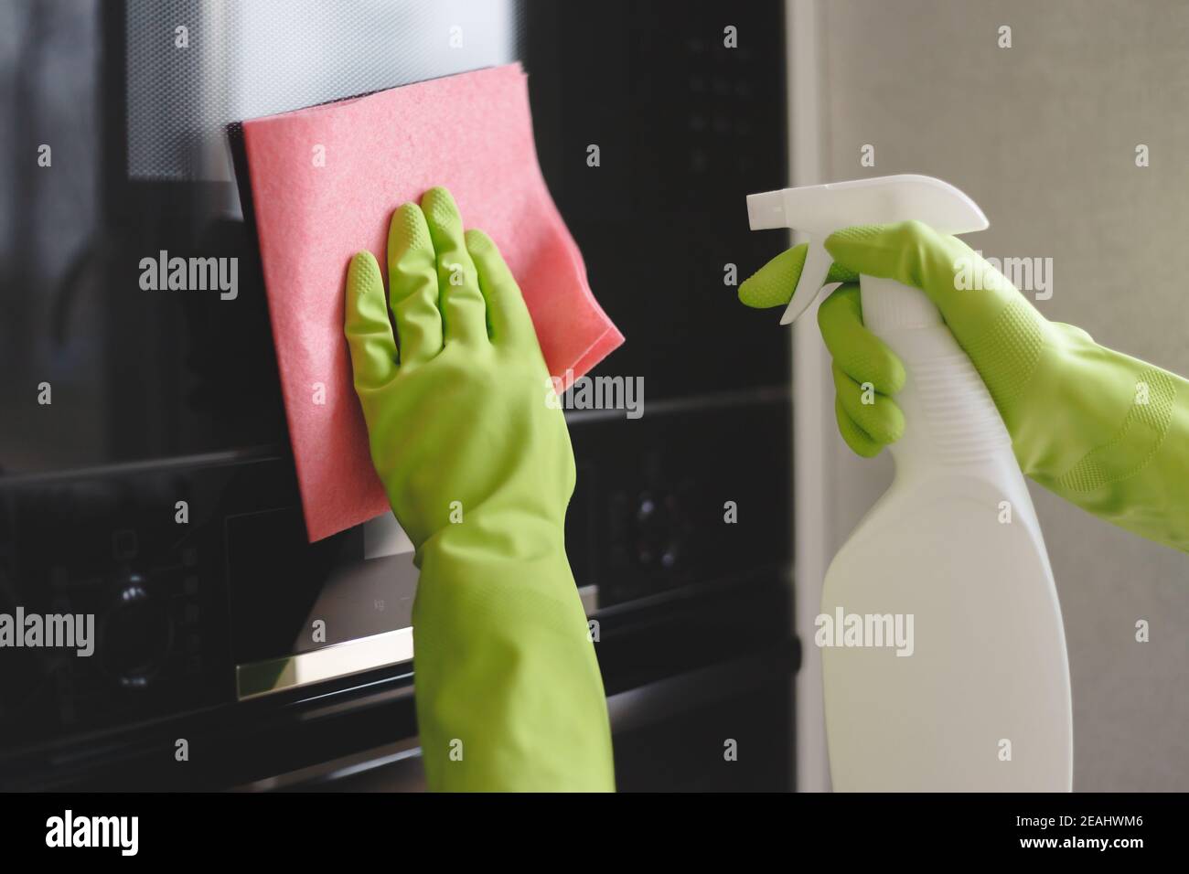 Donna di pulizia e forno microonde con uno straccio in cucina, close up Foto Stock