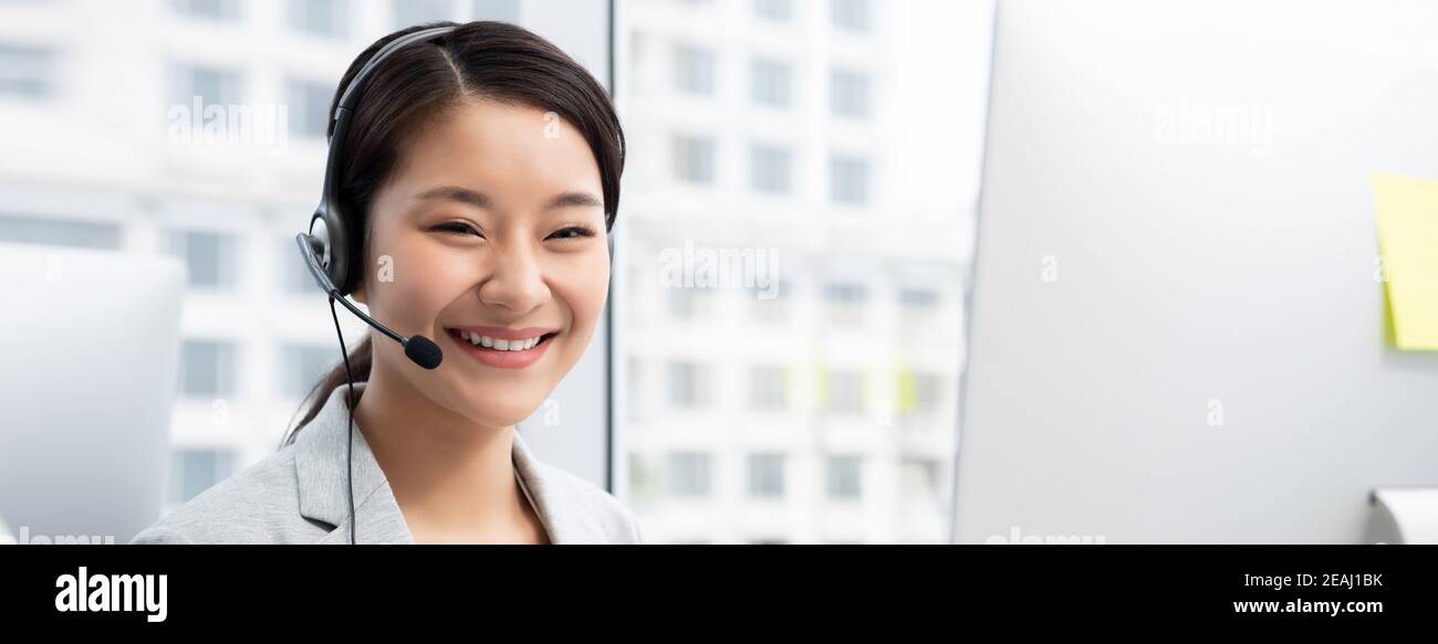 Sorridente, bella donna asiatica che lavora nell'ufficio del call center come operatore del servizio clienti Foto Stock