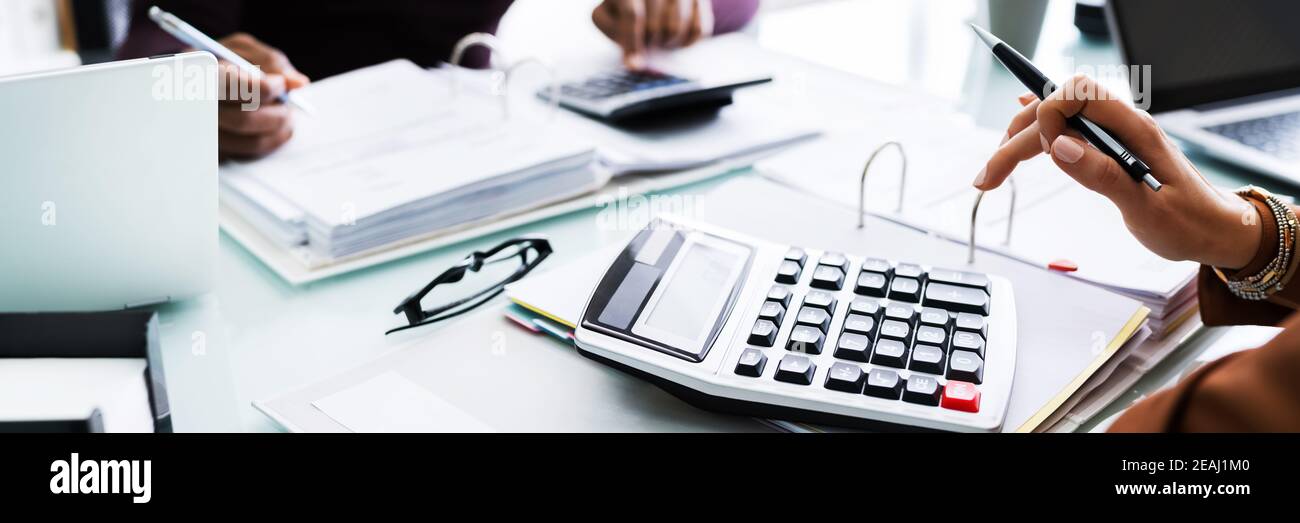 Due uomini d'affari che usano Calcolatrice sul luogo di lavoro Foto Stock