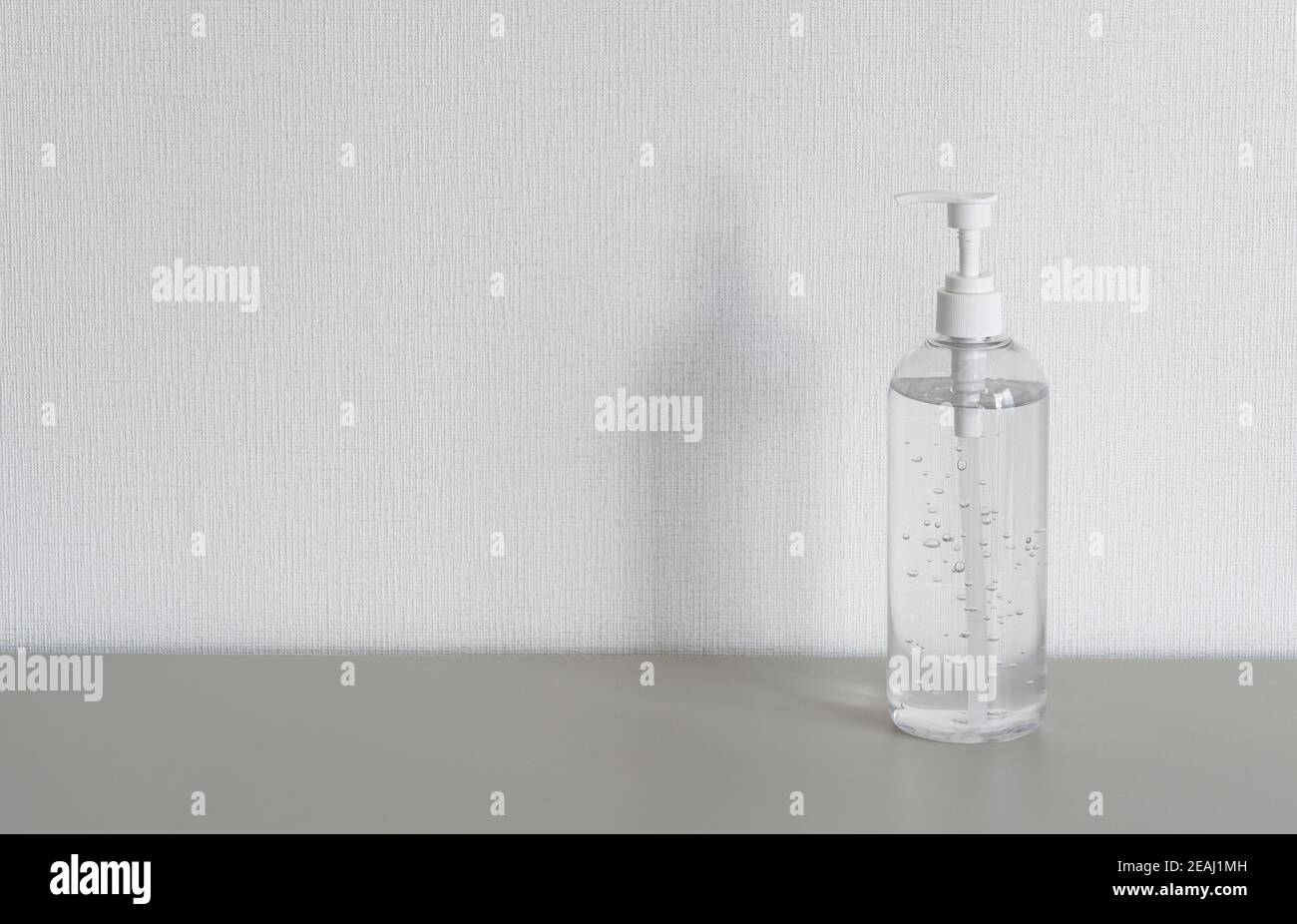 Una bottiglia di gel igienizzante davanti a una parete bianca. Foto Stock