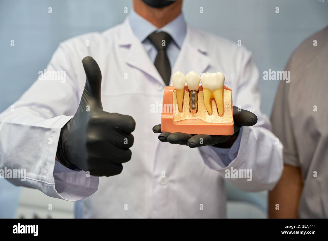 Tecnico dentale non riconosciuto in posa con il modello di impianto dentario Foto Stock