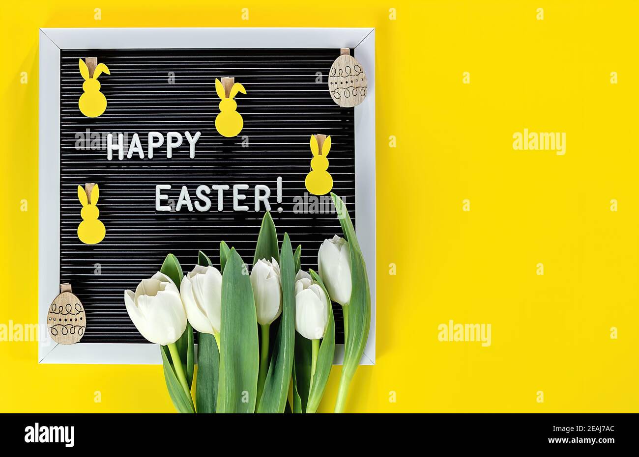 Coniglietto pasquale, fiori e cartellone su sfondo giallo. Piatto di concetto di celebrazione pasquale. Foto Stock