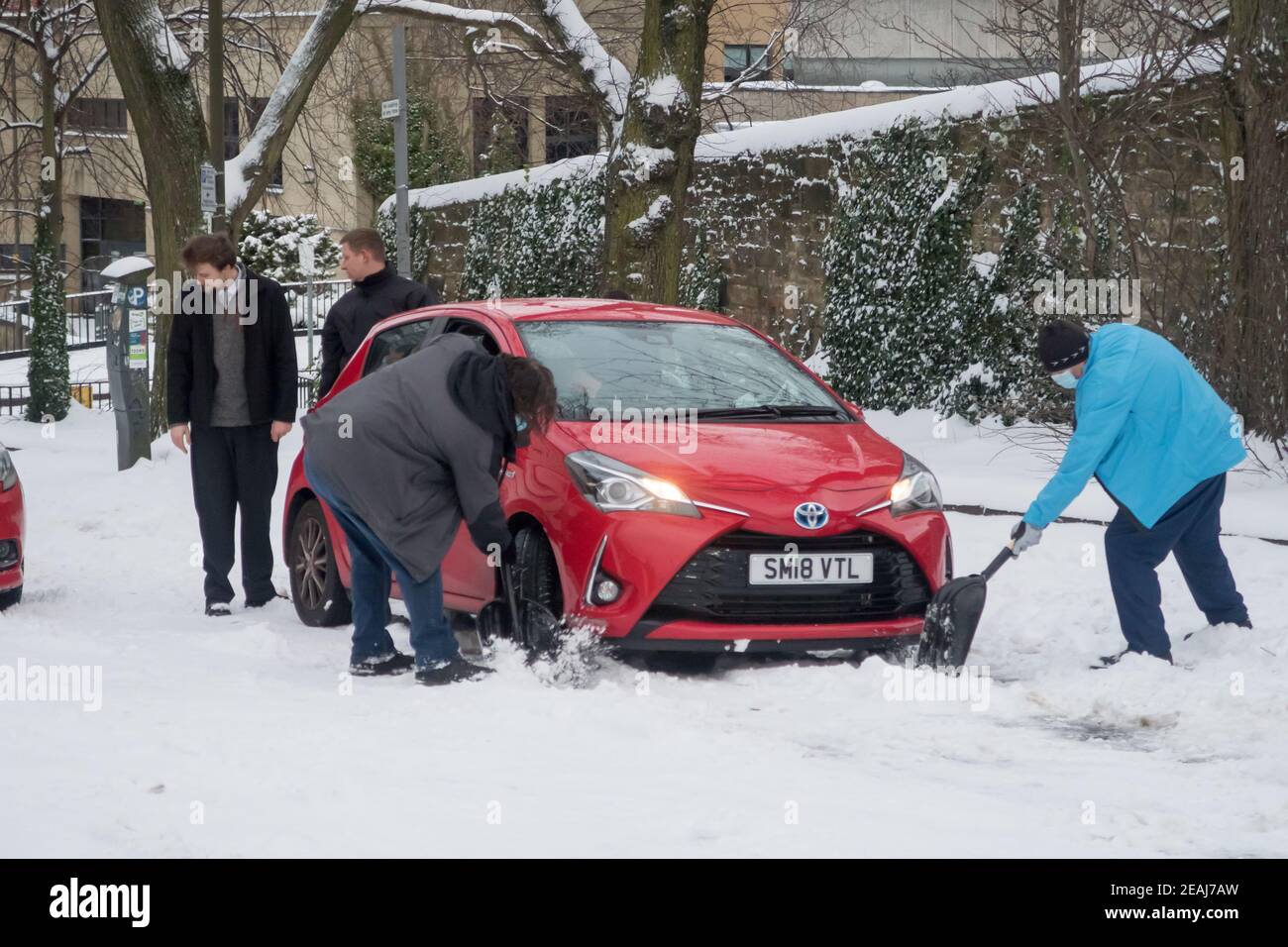Edimburgo, Scozia, Regno Unito. 10 febbraio 2021. A causa di una forte nevicata, il centro di Edimburgo è stato fermato questa mattina. I membri del pubblico che aiutano un conducente bloccato nella neve. Credit: Lorenzo Dalberto/Alamy Live News Foto Stock