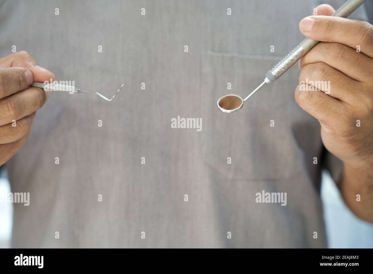 Tecnico dentale in posa con presa dentale e specchio Foto Stock