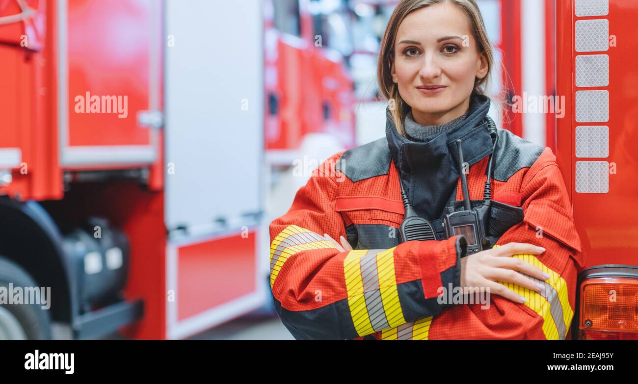 Donna vigile del fuoco che si trova di fronte a un camion dei pompieri Foto Stock