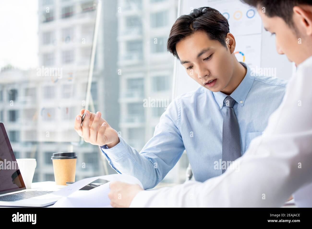 Uomo d'affari asiatico focalizzato discutere di dati e stato finanziario durante un incontro con il team in un ufficio moderno Foto Stock
