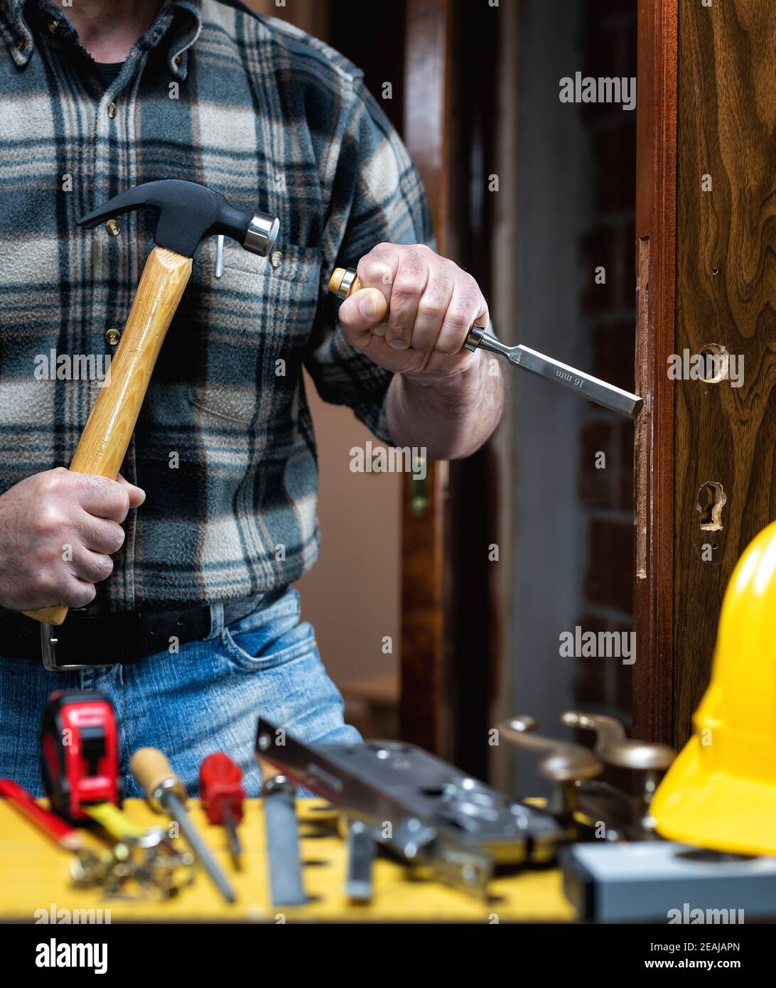 Falegname al lavoro ripara e installa la serratura della porta. Carpenteria. Foto Stock