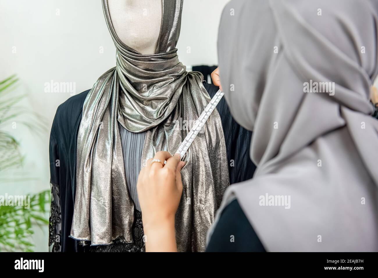Donna musulmana stilista di moda misura la taglia del vestito con nastro di misurazione in negozio su misura Foto Stock