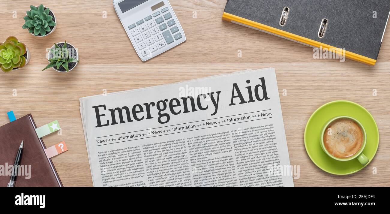Un giornale su una scrivania con il titolo Emergency Aid Foto Stock