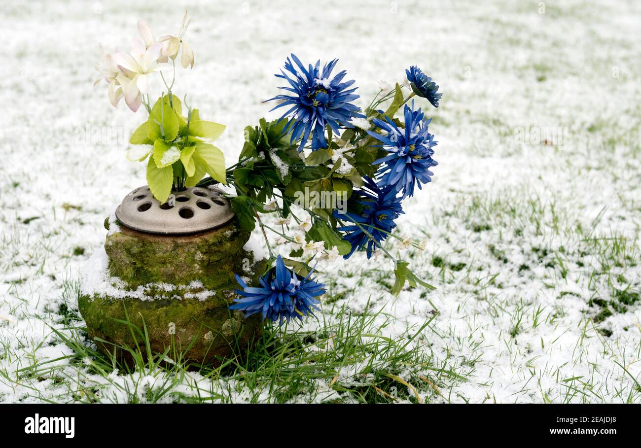 Fiori artificiali su una tomba in inverno, Warwick, Regno Unito Foto Stock