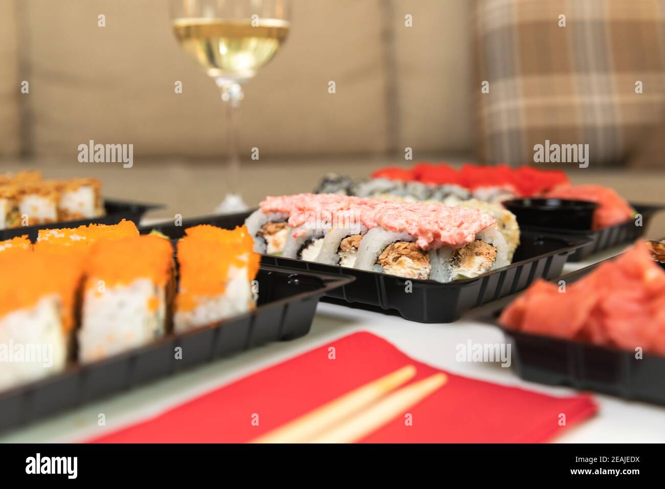 Un set di sushi colorati su un tavolo bianco con vino in una sala accogliente. Foto Stock