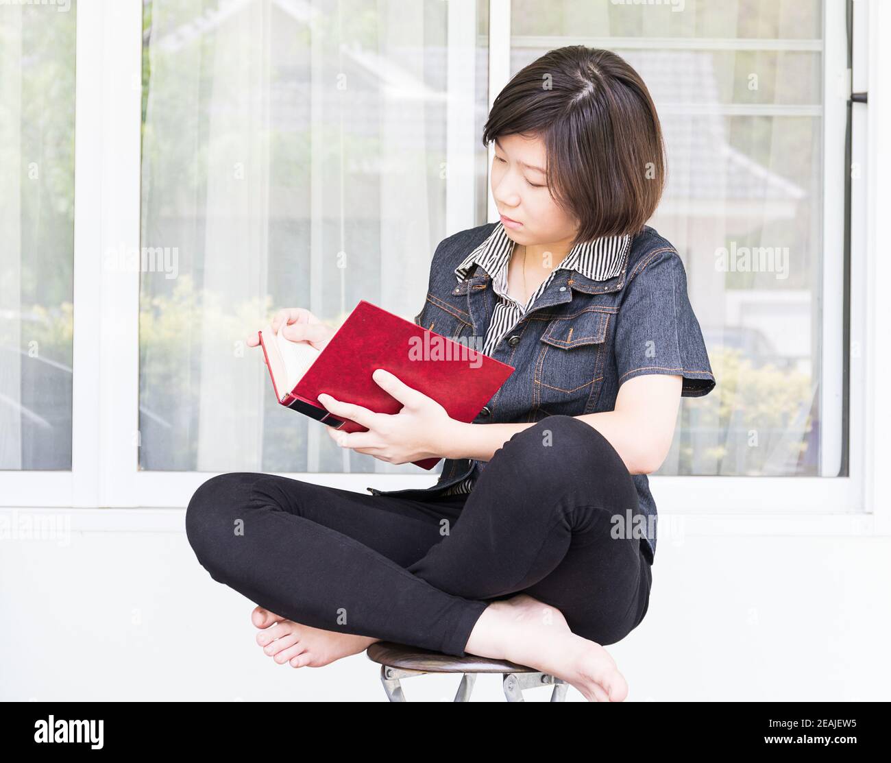 Giovane donna libro seduti su una sedia Foto Stock