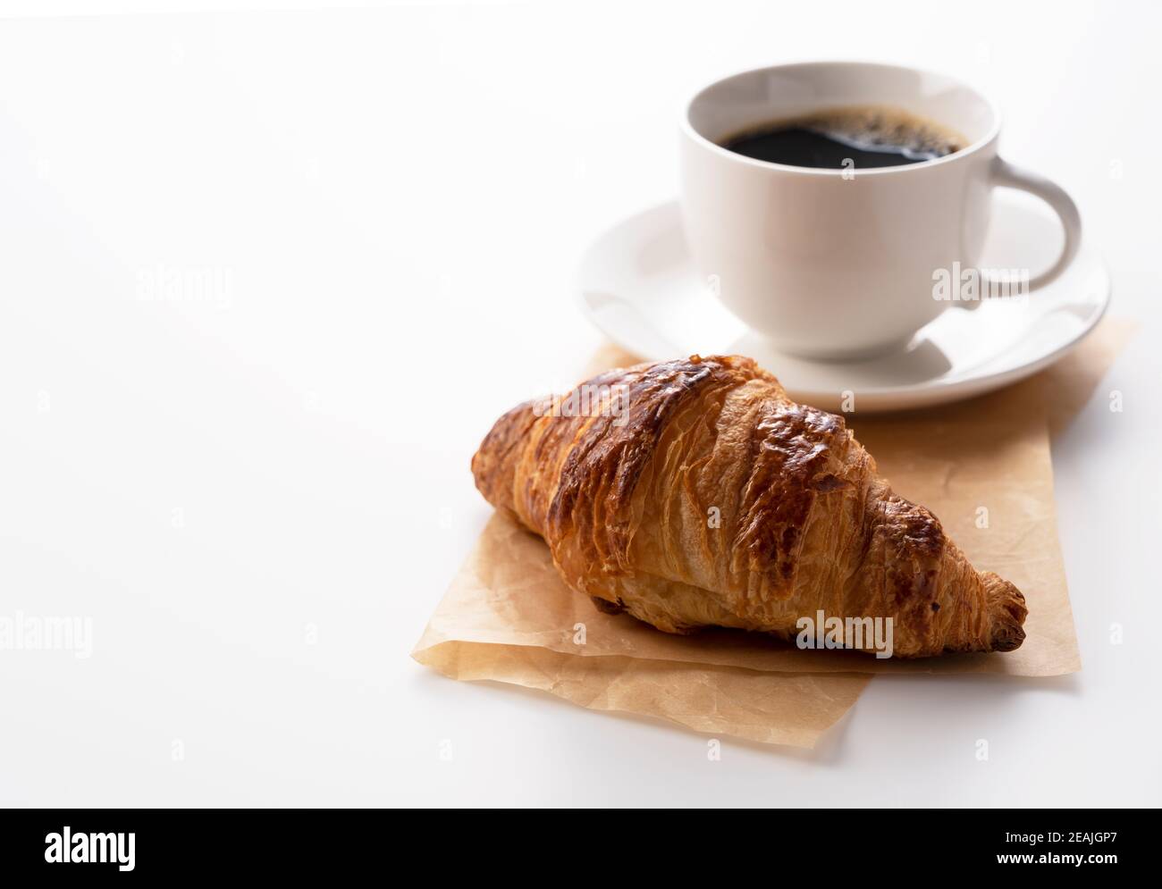 Croissant e caffè caldo su sfondo bianco Foto Stock